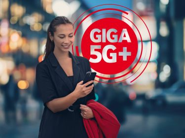 Eine Frau schaut auf ihr Smartphone das blitzschnell mit Giga 5G+ läuft