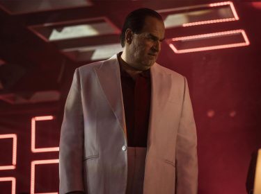 Auf dem Bild zu The Penguin-Serie ist Pinguin zu sehen. Er steht in einem rot gestalteten Raum und trägt ein weißes Sakko.