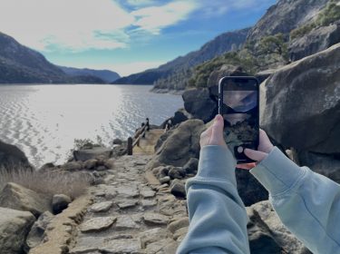 Zwei Hände halten iPhone zum Fotografieren eines Sees im Yosemite Nationalpark