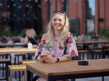 Junge Frau mit Handy im Straßencafè