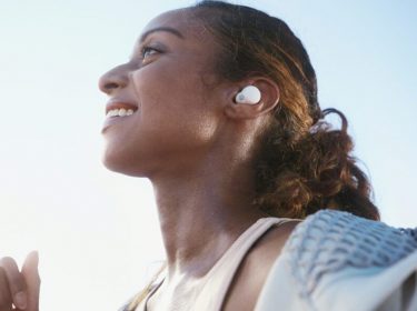 Lächelnde Frau unter freiem Himmel trägt Sony-Kopfhörer LinkBuds S