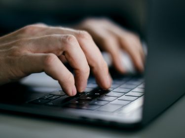 Männliche Hände tippen auf MacBook-Tastatur