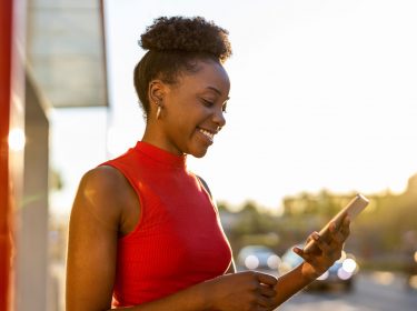 Frau mit Smartphone nutzt CallProtect, um Spam-Anrufe zu erkennen.