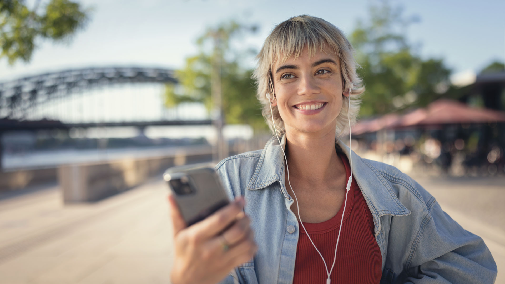 Eine Frau lächelt und hält ihr Smartphone in der Hand