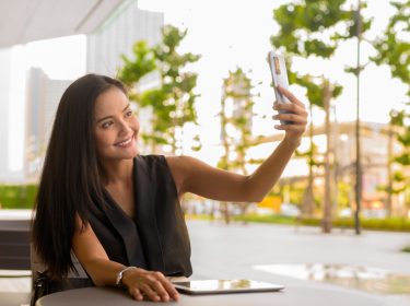 Elegante Frau im Cafè macht mit dem Smartphone ein Selfie