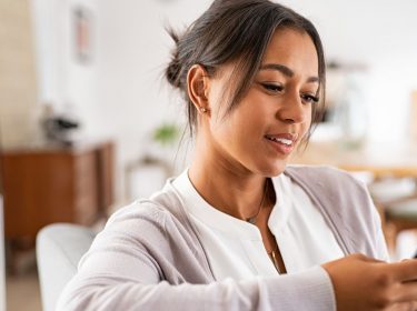 Frau liest WhatsApp-Nachricht auf ihrem Handy.