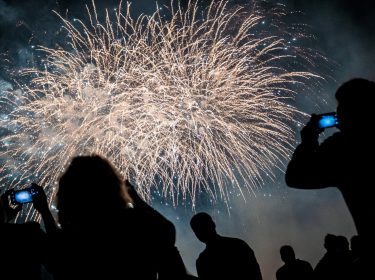 Silhouetten von Menschen, die ein Feuerwerk mit ihren Smartphones filmen