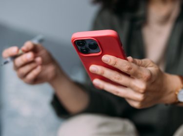 Mensch hält iPhone mit roter Hülle