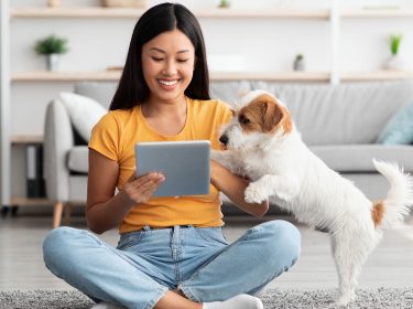 Frau spielt mit ihrem Hund via App