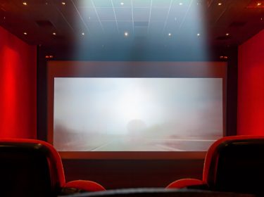 Roter Kinosaal mit Sessel und Leinwand