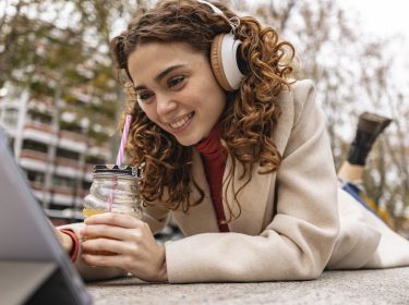 Junge Frau hört ein Hörbuch beim Browsen auf ihrem iPad