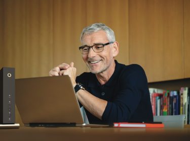 Ein Mann sitzt an seinem Laptop und loggt sich mit seinem Browser in das Router-Menü ein