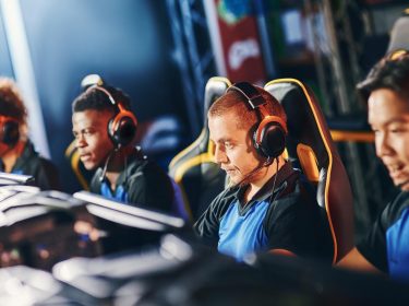 Vier Gamer:innen sitzen vor ihren Rechnern und spielen