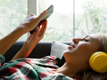 Spotify-Playlist exportieren: Frau mit Smartphone hört Musik.