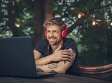 Mann mit Kopfhörern vor Laptop