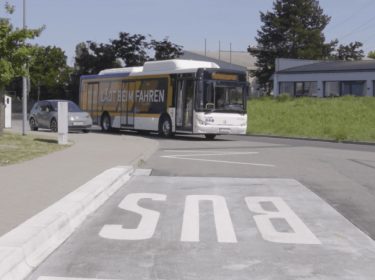 Ein E-Bus benutzt eine Straße für induktives Laden, die E-Autos beim Fahren auflädt