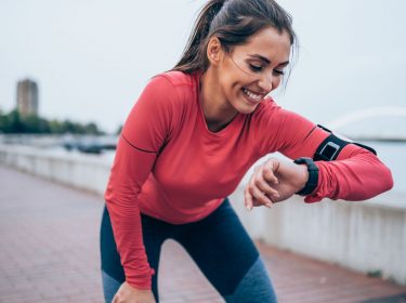 Frau schaut auf ihre Smartwatch beim Sport