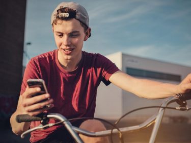 Junge auf Fahrrad mit Smartphone