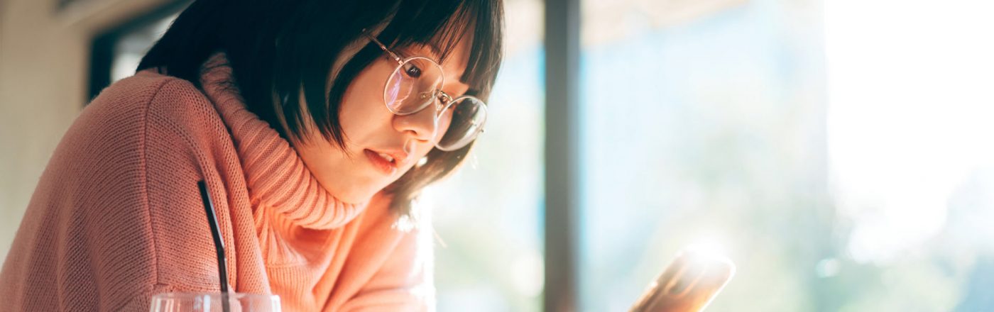 Mädchen schaut auf rosa Smartphone