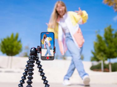 Ein Teenagermädchen filmt sich selbst mit einem Handy auf einem Stativ