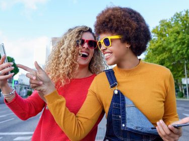 Zwei fröhliche junge Frauen mit Smartphone