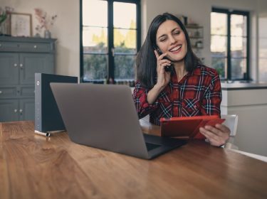 Frau am Telefon vor Laptop