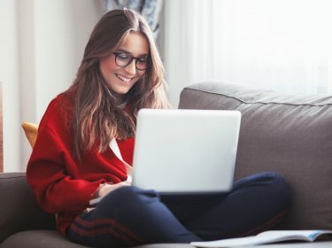 Studentin auf dem Sofa an ihrem Laptop beim Lernen