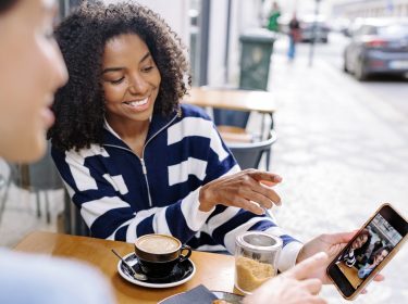 Zwei Frauen schauen sich Fotos auf einem Handy an.