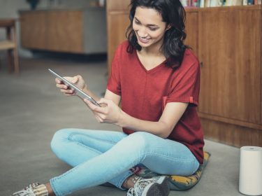 Junge Frau sitzt entspannt auf dem Boden neben dem GigaCube