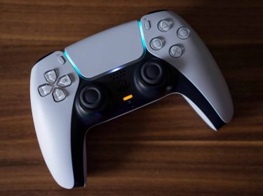 Ein PlayStation-5-Controller liegt auf einem Holztisch