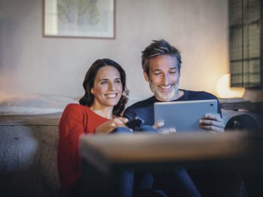 Paar schaut TV auf Fernseher und Tablet