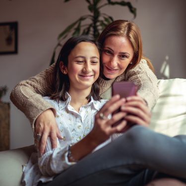 Auf dem Bild in dem Artikel zu den Vodafone Familientarifen ist eine Frau und eine junge Frau auf einem Sofa mit einem Handy zu sehen.