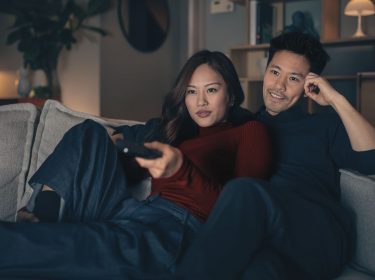 Mann und Frau sitzen gemeinsam auf dem Sofa und schauen einen Horrorfilm