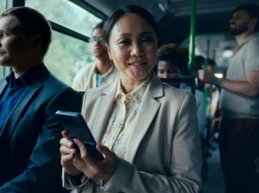 Frau sitzt mit Handy im Bus