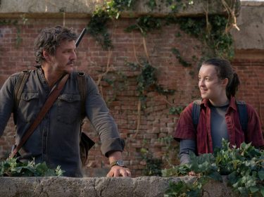 Joel und Ellie stehen vor einer Mauer und schauen sich an