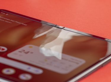 Smartphone Google Pixel Fold aufgefaltet auf rotem Untergrund liegend
