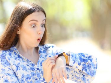 Überraschte Frau, die ihre Smartwatch in einem Park überprüft