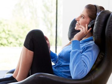 FRau mit Kopfhörern sitzt auf Sessel.