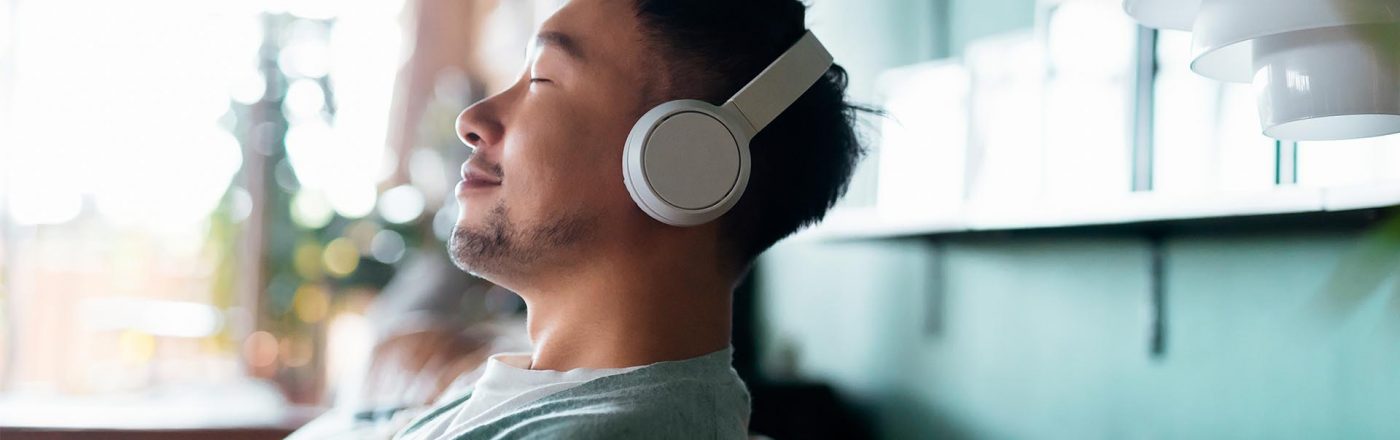 Ein junger Mann hört auf der Couch ein Hörbuch