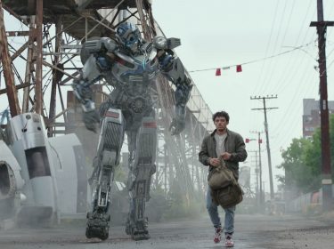 Noah (Anthony Ramos) und Transformer Mirage laufen nebeneinander eine Straße entlang im Film Transformers: Aufstieg der Bestien