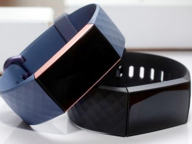 Zwei Versionen des Fitnesstrackers Fitbit Charge 3 in Blau und Schwarz liegen auf einer weißen Fläche