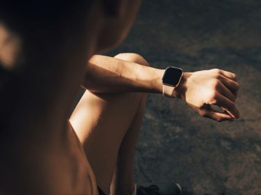 Frau schaut auf ihre Apple Watch am Handgelenk