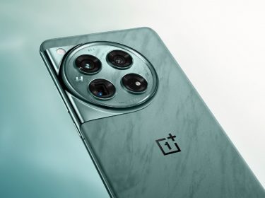 Die Rückseite des Smartphones OnePlus 12 mit rundem Kameramodul in Grün vor einem weiß-grünen Hintergrund