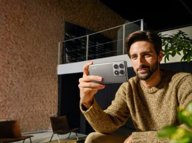 Junger Mann sitzt auf der Couch und schaut auf sein Xiaomi 14T Pro