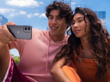 Ein junger Mann und eine junge Frau gucken unter freiem Himmel zusammen auf das Display des Handys Moto G24