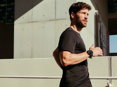 Mann läuft in der Stadt der Sonne entgegen mit OnePlus Watch 2 am Handgelenk