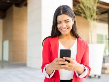 Frau schaut lächelnd auf ihr Android-Smartphone