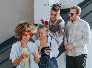 Vier junge Leute amüsieren sich mit ihren Smartphones.