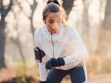 Eine Sportlerin checkt ihre Smartwatch beim Joggen