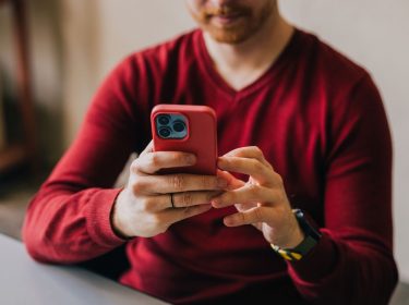 Mann tippt auf seinem roten iPhone